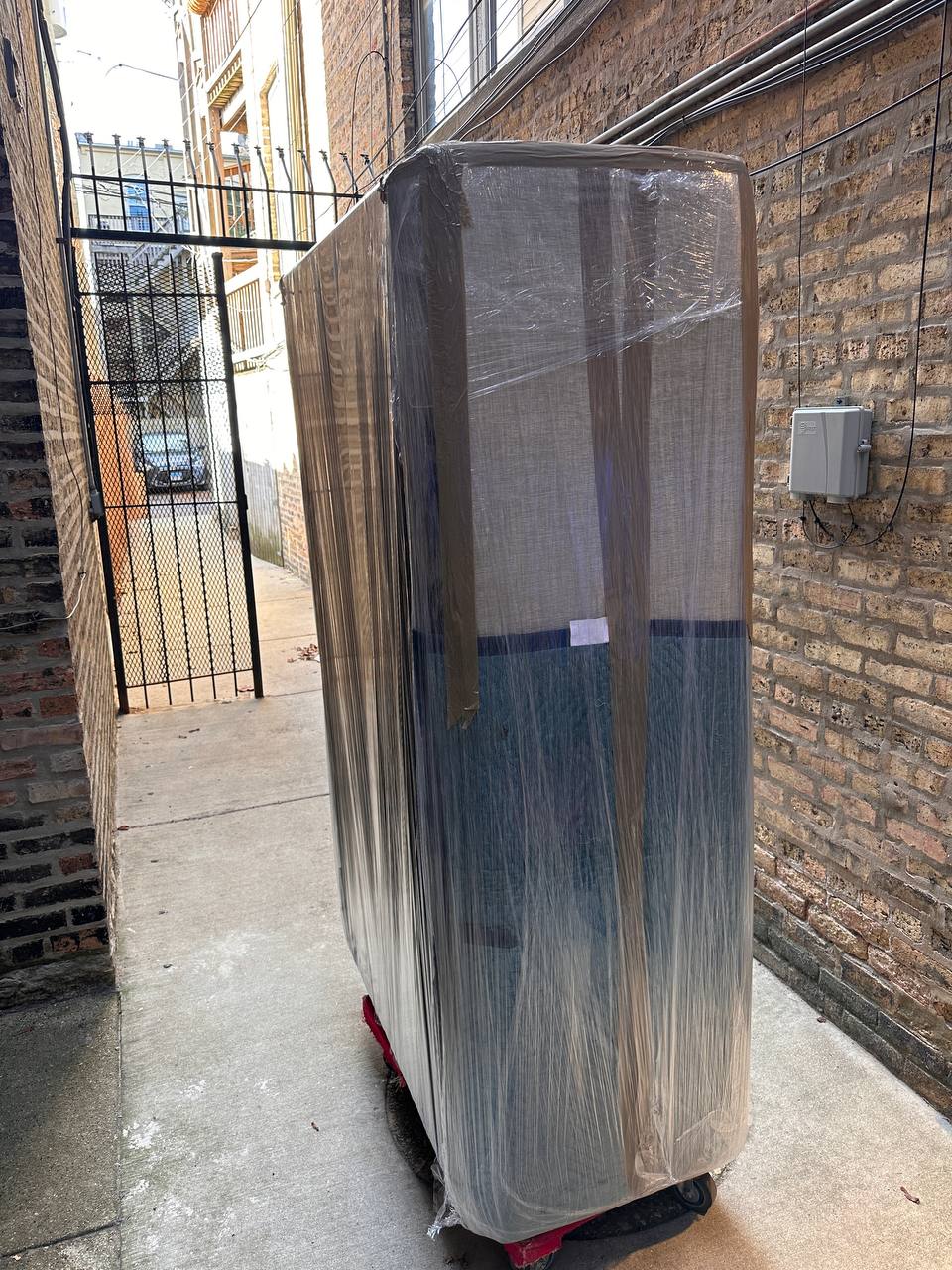 Large wrapped furniture on dolly in alley